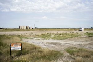 This is a highly impacted area near Antler, North Dakota in Bottineau county. In the distance you can see a slew of wells that are considered legacy wells from the previous booms. In the foreground you can see a secondary recovery injection well. Notice the washed out areas where the vegetation has been killed by the chlorides and other contaminants. Photo by David Nix 2015